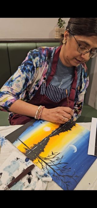 Art Club member painting a sunset tree scene