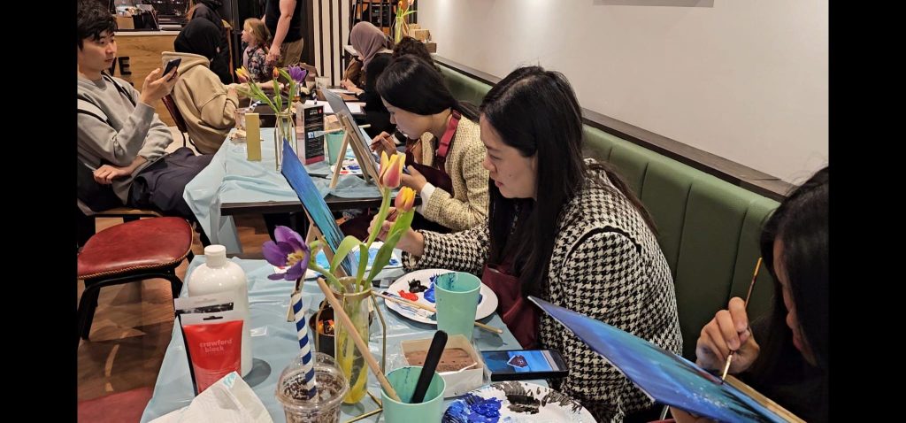 Art Club members painting around a table at a Devi Arts session