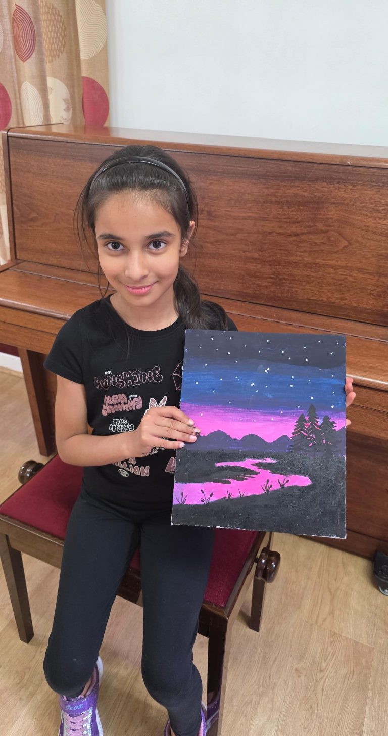 A student proudly showing off her finished night-sky painting