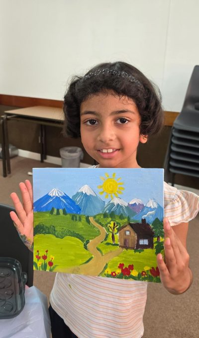 Young student smiling, holding a landscape painting of her own design